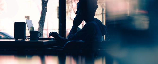 silhouette of a person sitting in front of a laptop